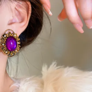 Detailed macro shot of elegant vintage French purple oval pearl clip earrings.