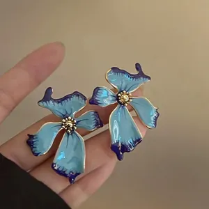Close-up of blue and purple enamel fan-shaped earrings with gold detailing