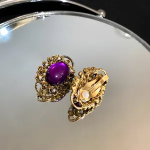 Detail view showing French vintage gold-tone clip-on earrings with a purple oval stone.