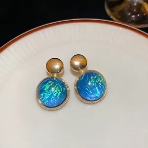 Macro view of blue iridescent round stud earrings with elegant gold metallic accents