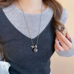 Gedetailleerd overzicht van een zilveren paard hanger ketting gedragen op een grijze trui.
