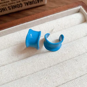 Detailed close-up view of bright blue irregular C-shaped fold design stud earrings.