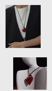 Dettaglio di una collana con ciondolo a cuore irregolare rosso e cordoncino nero