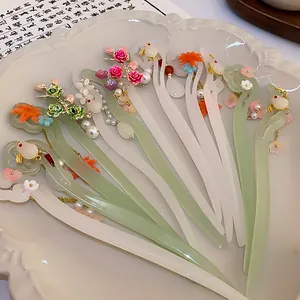 Detailed view of assorted Chinese style floral hair sticks with pearl accents on a white plate
