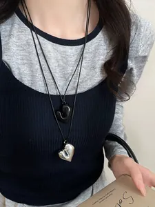 Dettaglio della collana con ciondolo a cuore irregolare e cordino in pelle regolabile.