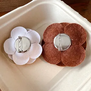 Detailed back view of elegant flocked camellia flower brooches with metal safety pins