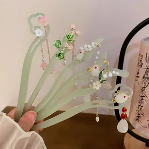 Detail view of pale green traditional Chinese hair sticks with floral and rabbit charms
