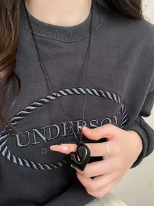 Primo piano di un ciondolo a cuore nero irregolare su una collana in pelle regolabile alla moda.