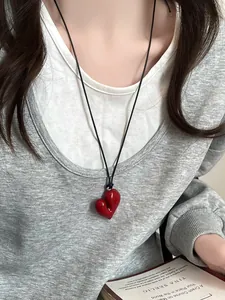 Dettaglio di una collana con ciondolo a cuore rosso irregolare su un cordino nero