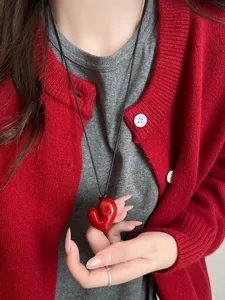 Dettaglio ravvicinato della collana con pendente a cuore rosso irregolare lucido con cordino nero