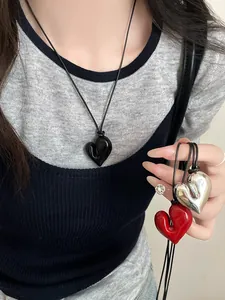 Primo piano di ciondoli a forma di cuore irregolari con finiture nero, rosso e argento