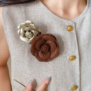 Close-up of elegant leather and flocked camellia flower brooches on tweed