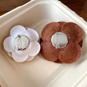 Detailed back view of elegant flocked flower brooches showing metal safety pin mechanisms.