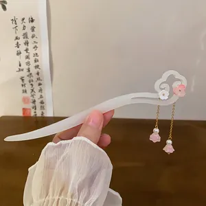 Macro view of a neo-Chinese hairpin with white cloud motif and pink floral tassels.
