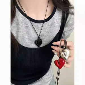 Dettaglio di pendenti a cuore irregolari in nero, rosso e argento su cordini in pelle