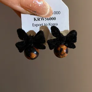 Dettaglio ravvicinato di orecchini a fiocco floccato nero con perle motivo leopardo