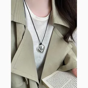 Dettaglio della collana con ciondolo a cuore in argento irregolare su cordoncino di cuoio nero.