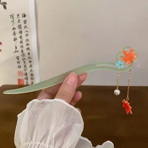 Detailed view of a light green resin hair stick with maple leaf and pearl tassels