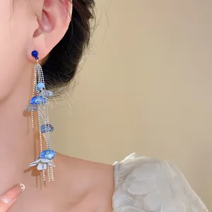Detalle de pendientes largos con borlas de cuentas de vidrio azul y detalles de flor