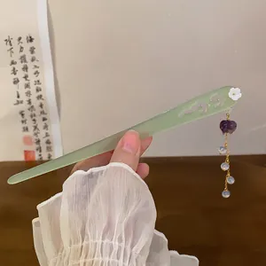 Close-up of an elegant jade-like hair stick with flower and purple tassel detail