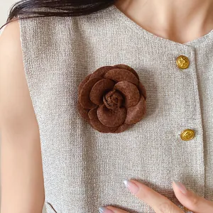 Detail view of a vintage brown flocked leather camellia flower brooch on tweed jacket
