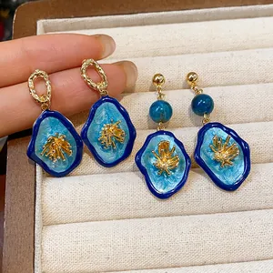 Detailed macro view of blue resin flower earrings with elegant gold finish accents