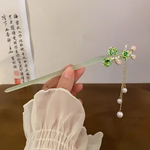 Detail of a pale green Chinese style hair stick with floral accents and pearl tassels.