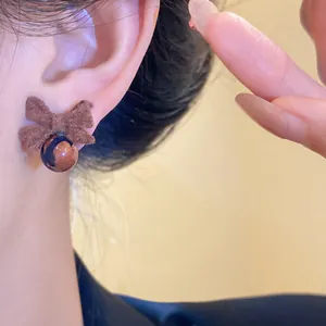 Dettaglio ravvicinato di un orecchino a fiocco floccato marrone con perla di sabbia d'oro