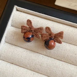 Macro dettagliata di orecchini vintage con fiocco marrone floccato e perle marmoree