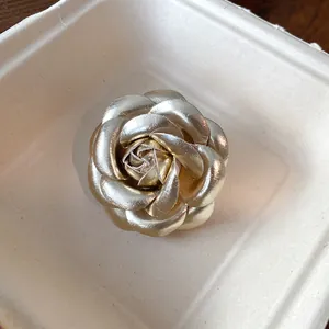 Detailed view of elegant gold leather camellia flower brooch with metallic finish