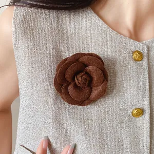 Elegant brown flocked rose flower brooch pinned on a stylish beige textured vest accessory