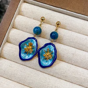 Close-up detail of vintage blue enamel flower earrings with stone bead and gold accents