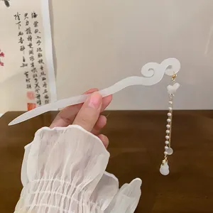 Macro detail of white translucent Chinese hair stick featuring pearl tassel and cloud scroll