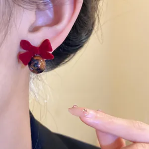 Dettaglio degli orecchini a fiocco rosso floccato con pendente a sfera dorata