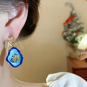 Close-up detail of new Chinese style blue floral earrings with gold accents on model