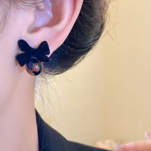 Primo piano di un orecchino a fiocco nero floccato con perla indossato sull'orecchio