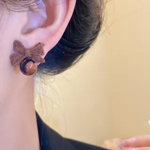 Primo piano dell'orecchino a fiocco floccato marrone vintage con perla a galassia luccicante
