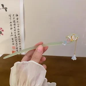 Detail of a green Chinese style hair stick with butterfly and flower tassel detail