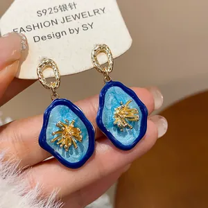 Macro view showing the blue enamel texture and gold floral center of the vintage earrings.
