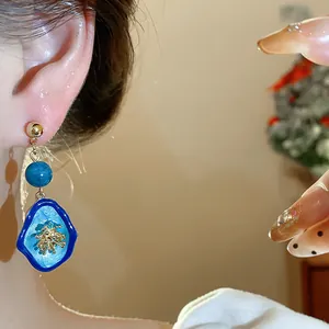 Detailed macro shot of vintage blue stone flower earrings worn by a female model