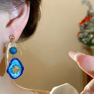 Close-up of blue stone flower earring with gold details on model's ear