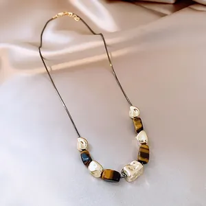 Close-up of vintage necklace featuring irregular gold beads and artificial tiger eye stones.