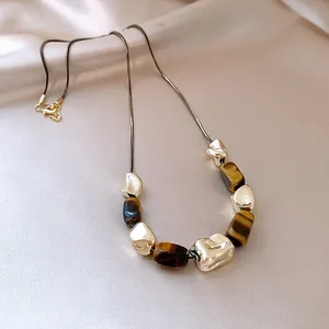 Detail view of irregular wrinkled gold metal and faux tiger eye stone necklace