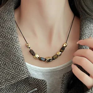Close-up of irregular gold beads and faux tiger eye stone necklace on neck