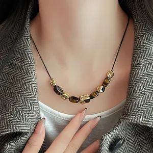 Detailed view of irregular artificial tiger eye necklace with golden pleated beads on neck