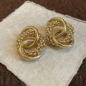Detailed view of elegant gold knotted stud earrings with smooth and beaded texture.