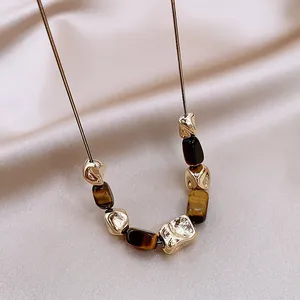 Detail of irregular faux tiger eye stone necklace with gold-tone wrinkled beads on silk.