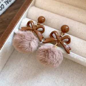 Detailed view of elegant brown bowknot earrings with soft pink fur pom-pom accents