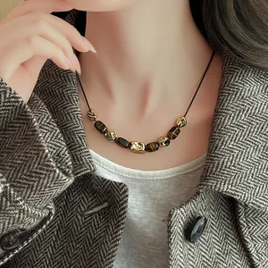 Detail shot of irregular gold wrinkled beads and tiger eye stone necklace on a model