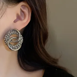 Close-up of stylish silver knotted hoop earrings with beaded and smooth texture